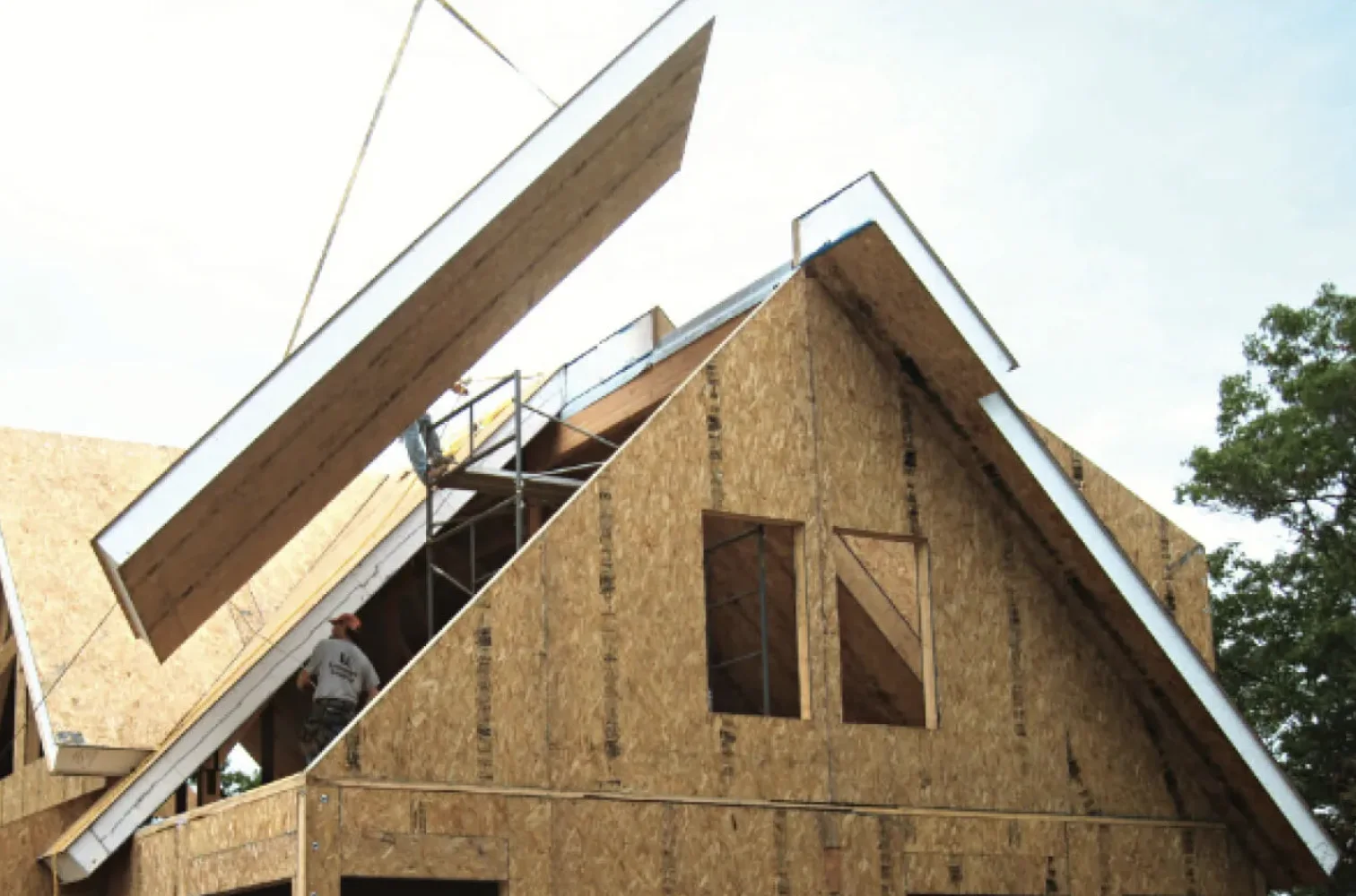 Large insulated roof panels being lifted into position over a residential building